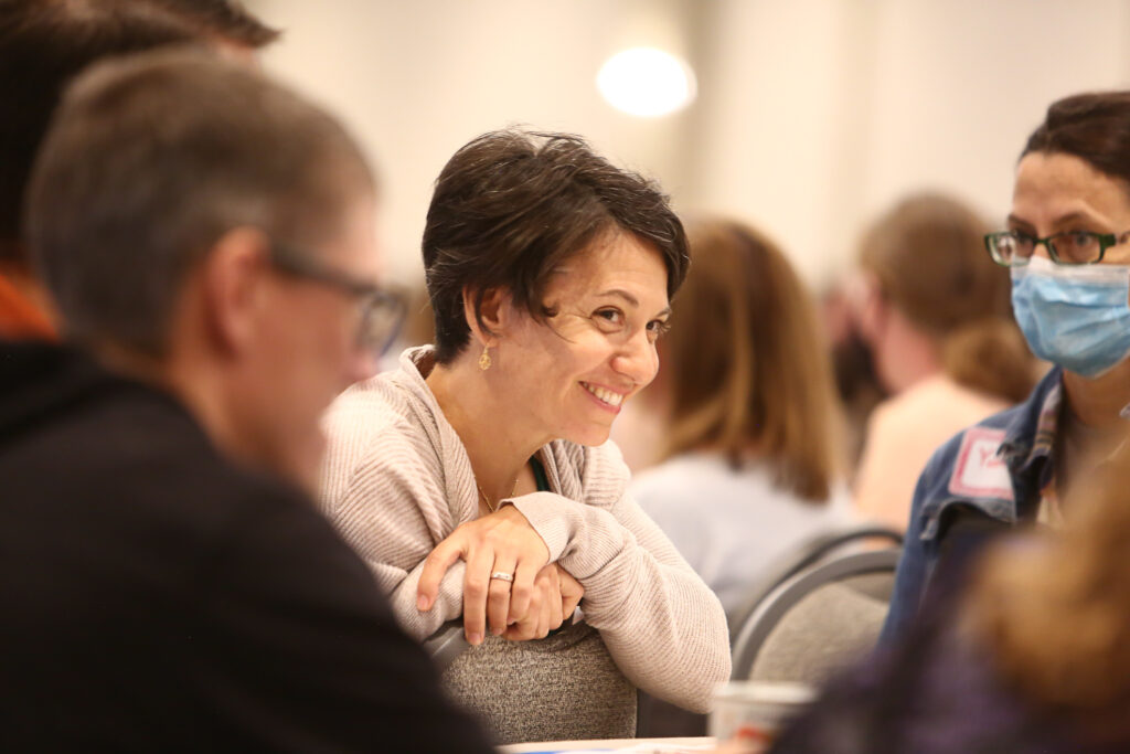 woman smiling at a table with others who are blurred