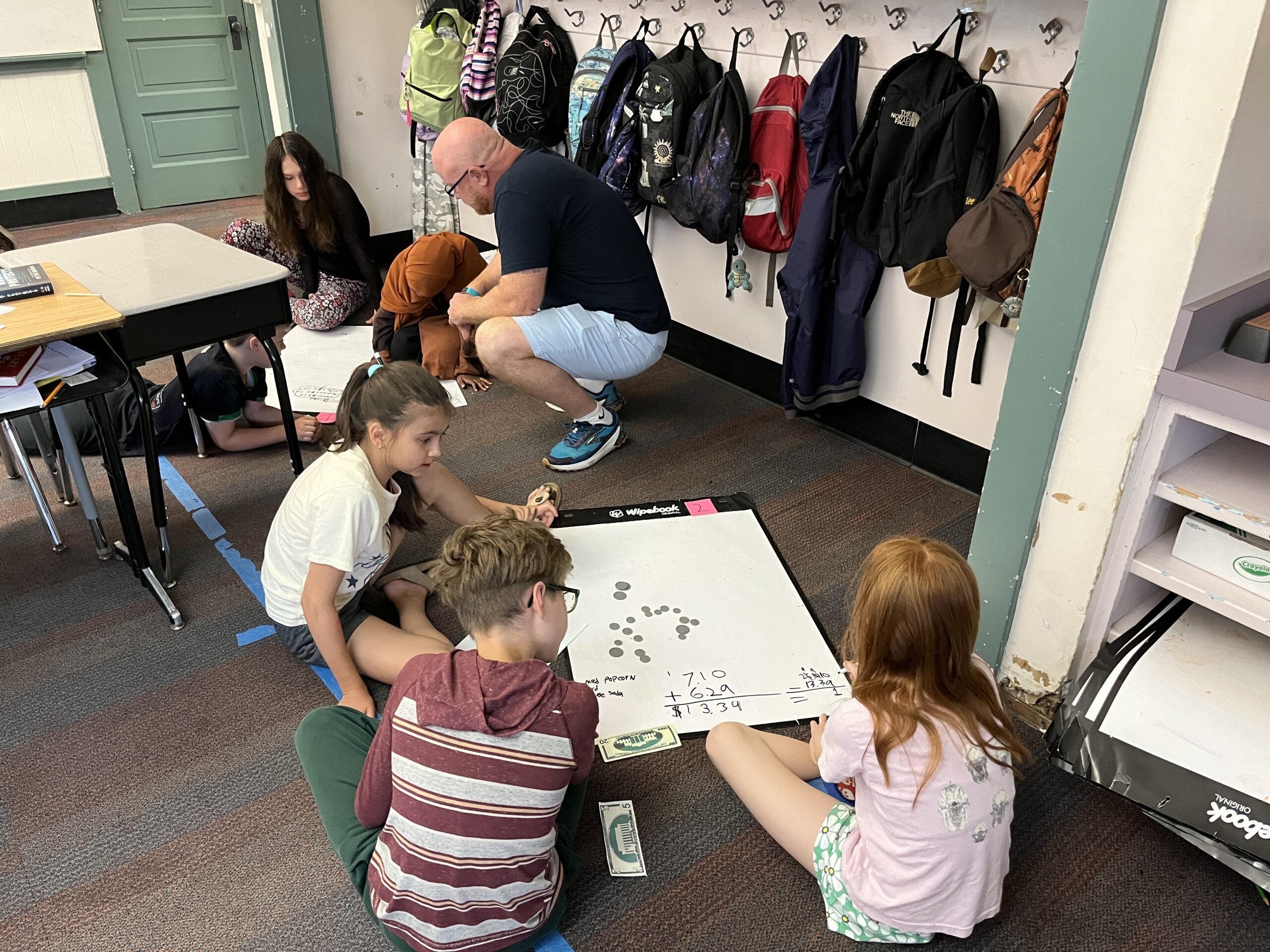 Students doing math problems with pretend paper money and coins