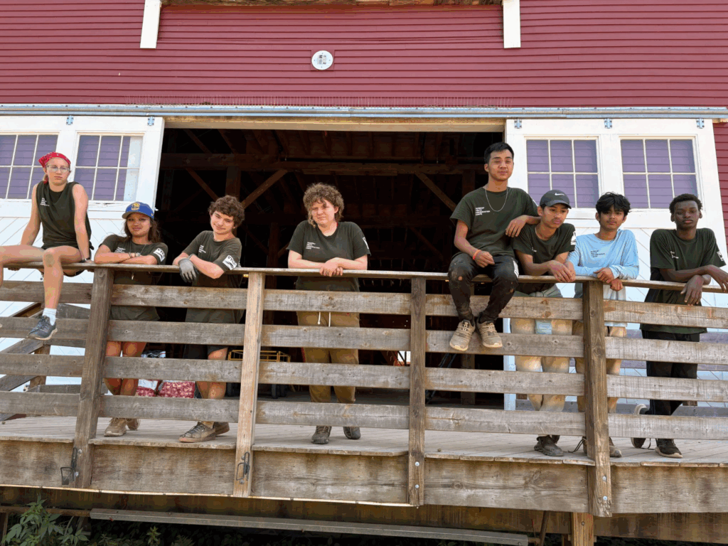 8 students posing on a wooden deck