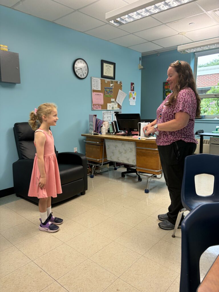 A student smiling while meeting with a school nurse